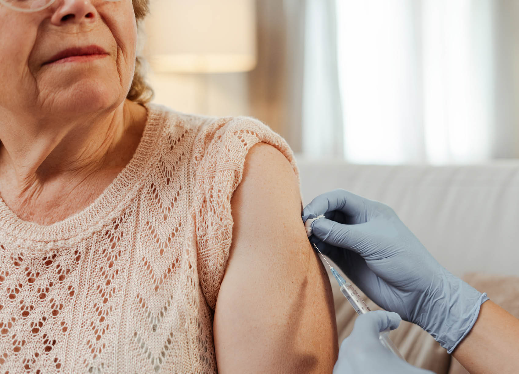 Doctor vaccinating a senior woman at home, ensuring her well-being and safety. Vaccination, elderly, healthcare concept